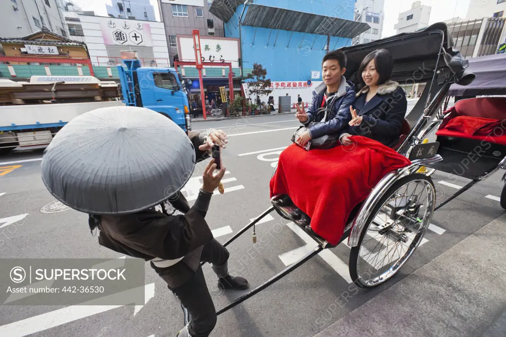 Rickshaw driver taking picture of a couple, Asakusa, Tokyo, Japan