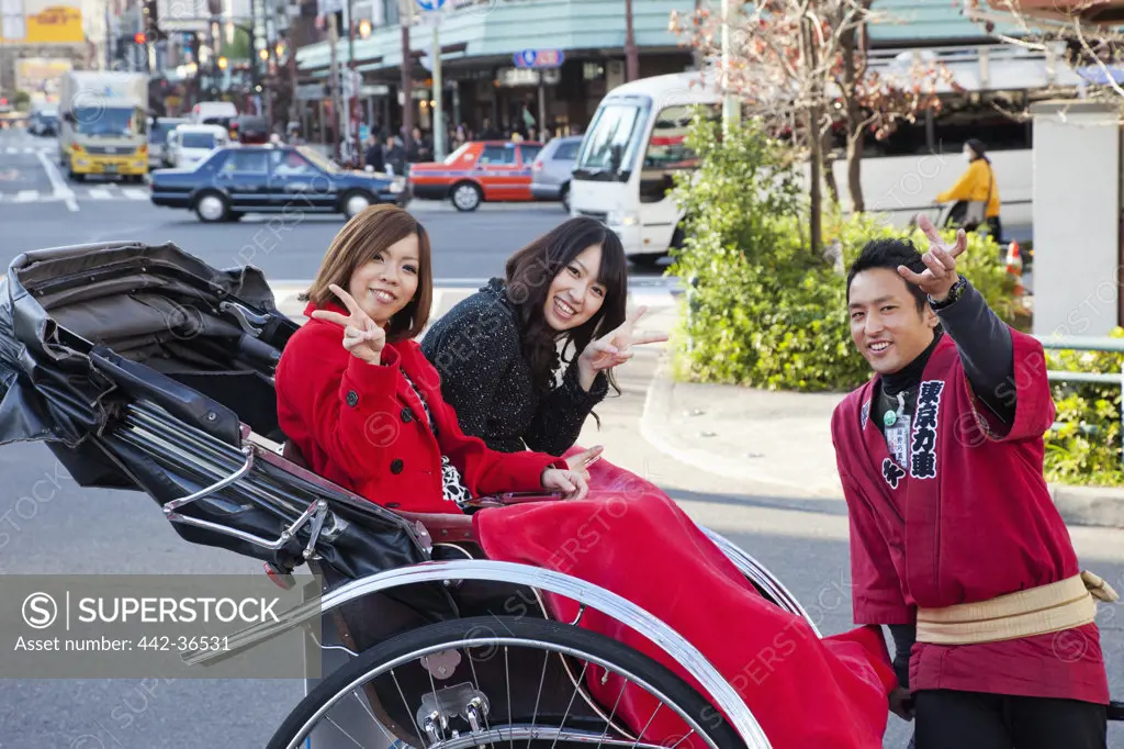 Tourists sitting in a rickshaw and showing victory sign, Asakusa, Tokyo, Japan