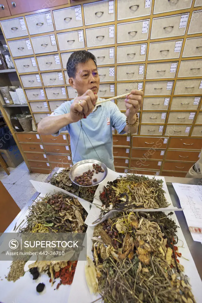 Pharmacist weighing ingredients for Chinese medicine prescription, Sheung Wan, Hong Kong, China