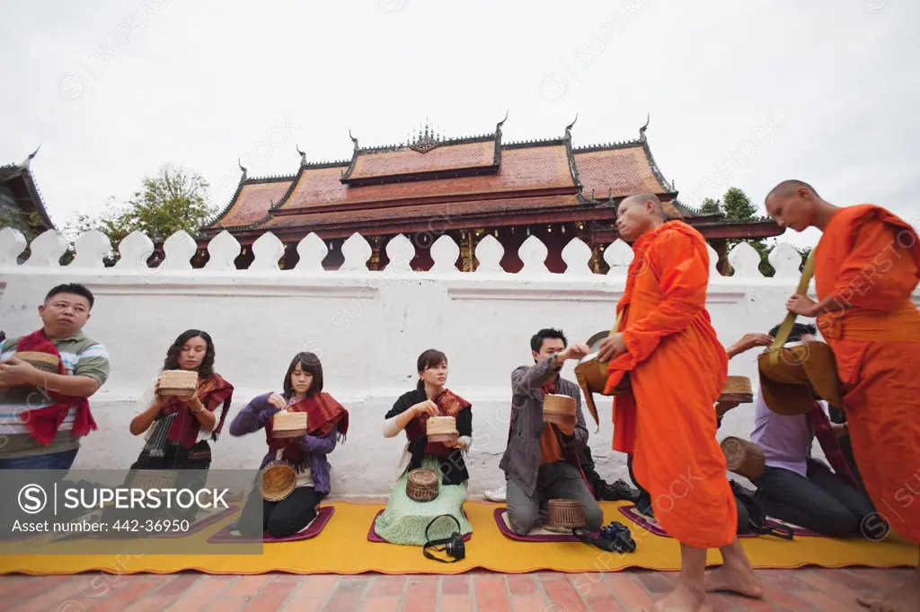 Tourists giving offerings to monks, Wat Sensoukarahm, Luang Phabang, Laos