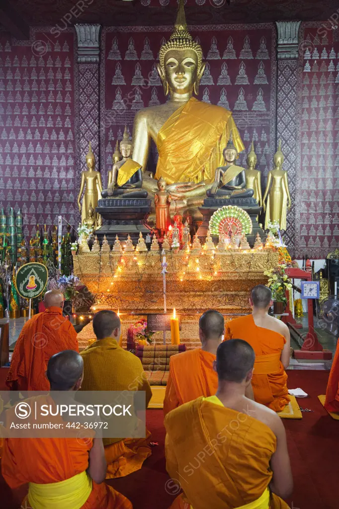 Monks praying in the main prayer hall, Wat Phone Xai, Luang Phabang, Laos