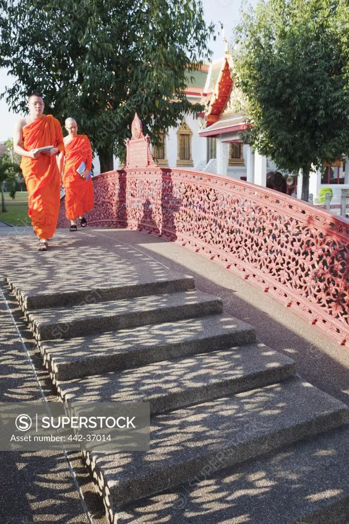 Two monks Walking in the temple grounds Wat Benchamabophit (also known as the Marble Temple), Bangkok, Thailand