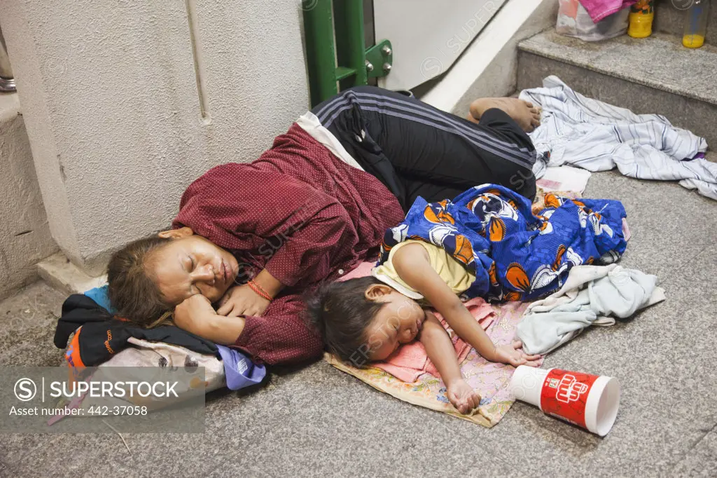 Homeless woman sleeping with daughter on footpath, Bangkok, Thailand