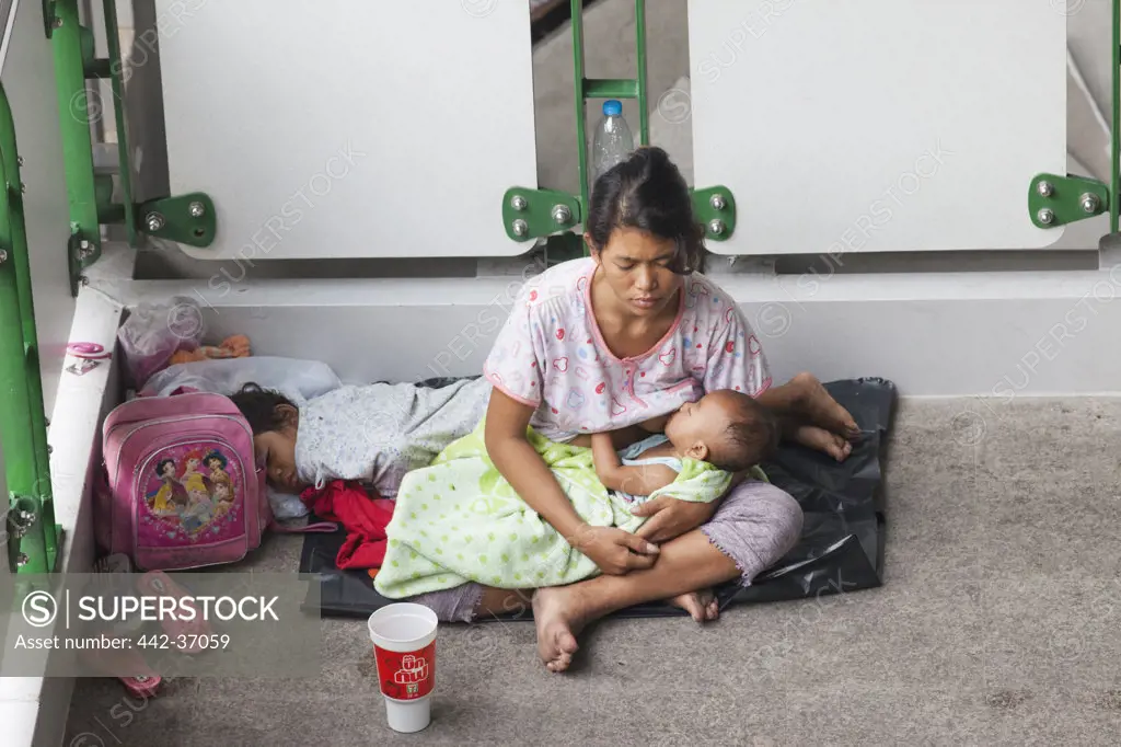 Homeless woman nursing her bay and begging, Bangkok, Thailand