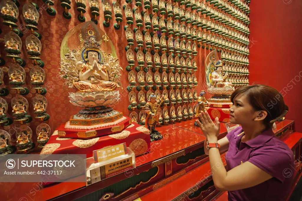 Woman praying in a Buddhist temple, Buddha Tooth Relic Temple And Museum, Chinatown, Singapore