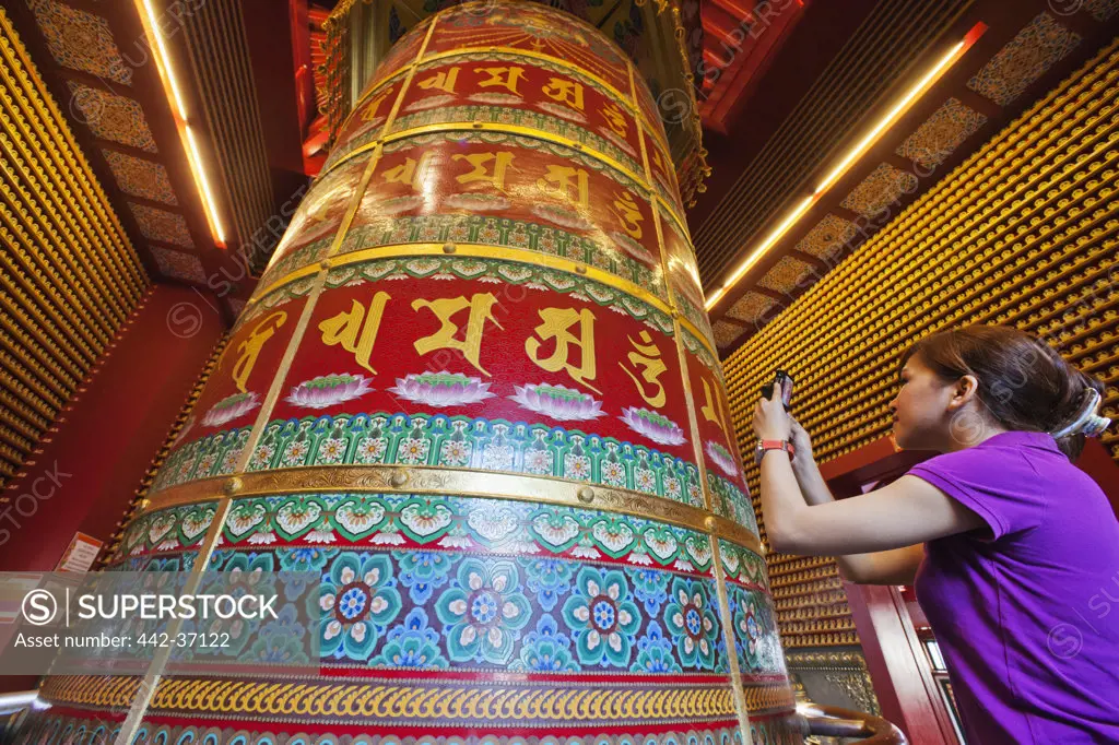 Woman taking picture of Vairocana Buddha Prayer Wheel, Buddha Tooth Relic Temple And Museum, Chinatown, Singapore