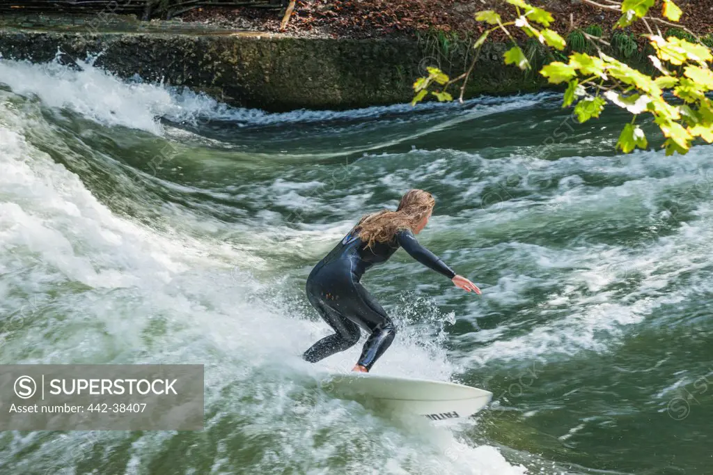 Woman surfing in a river, Eisbach River, English Garden, Munich, Bavaria, Germany