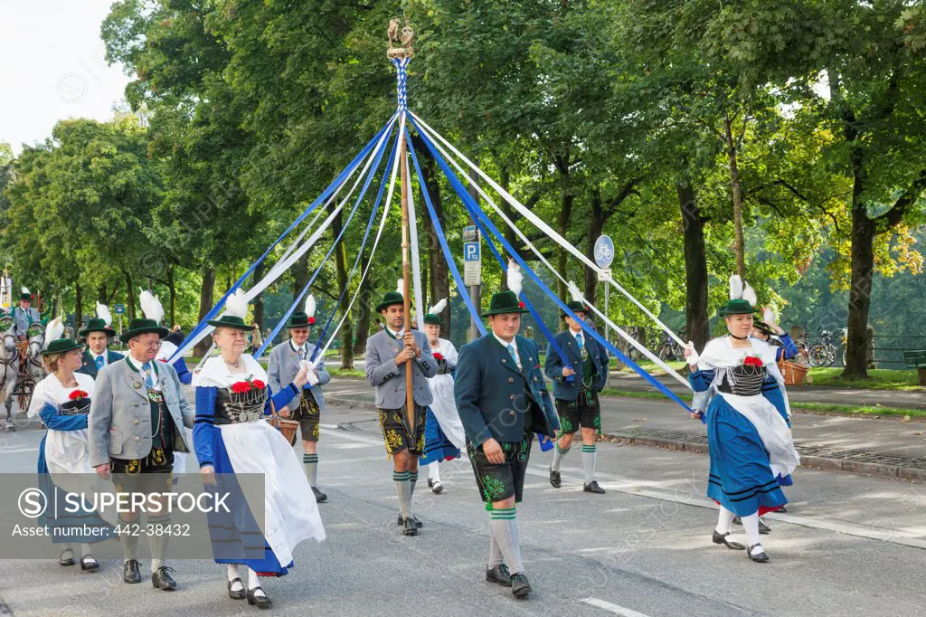 People in Traditional regional costume carrying maypole during Oktoberfest Parade, Munich, Bavaria, Germany