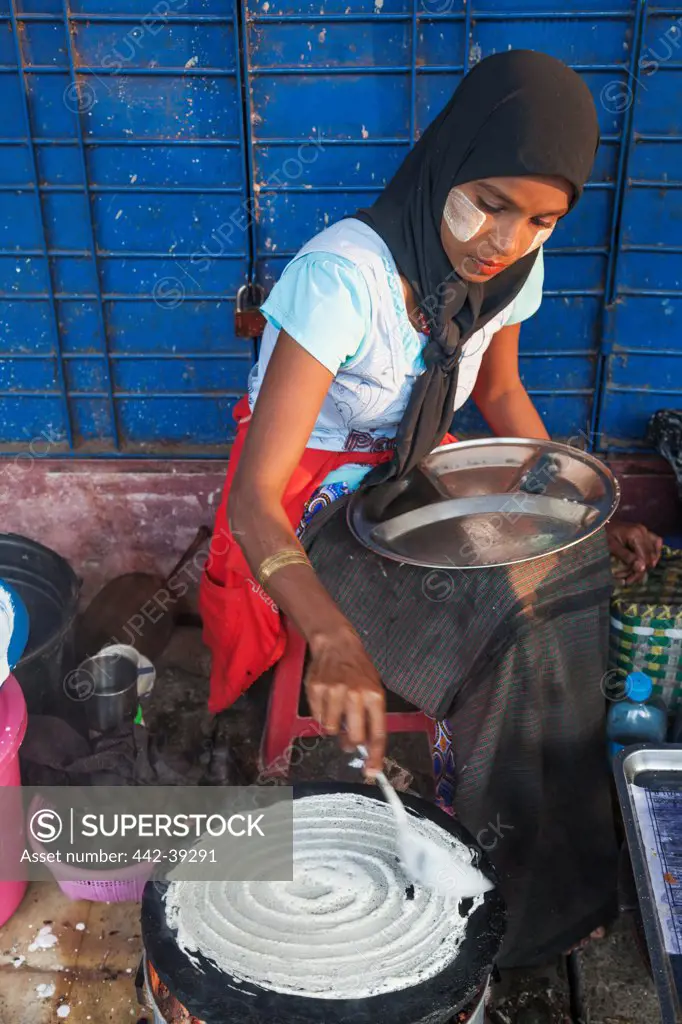 Burmese woman cooking Indian style crepes, Yangon, Myanmar