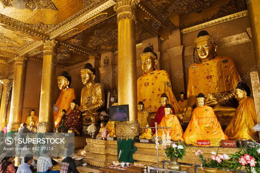 People praying in front of Buddha Statues in a temple, Shwedagon Pagoda, Yangon, Myanmar