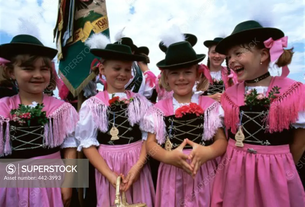 Four girls smiling and standing in a Bavarian festival, Rosenheim, Germany