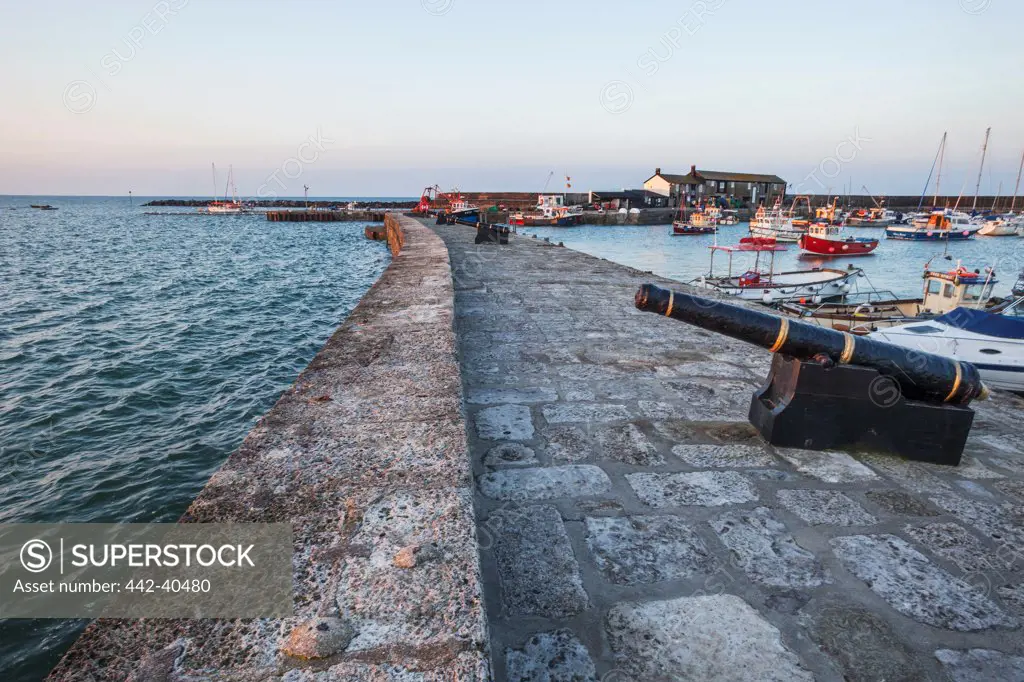 Cannon on a jetty at a harbor, The Cobb, Lyme Regis, Dorset, England
