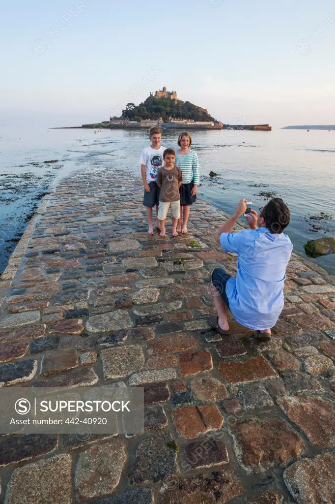 Man taking pictures of his family on the jetty, St. Michael's Mount, Marazion, Cornwall, England