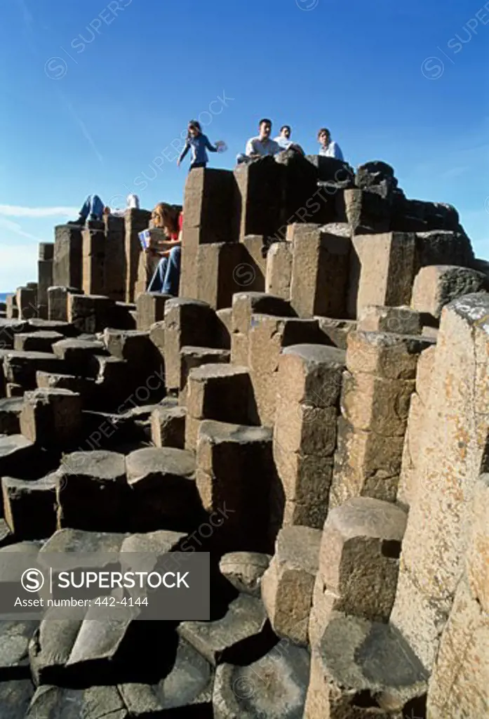 Low angle view of tourists on volcanic rocks, Giant's Causeway, County Antrim, Northern Ireland