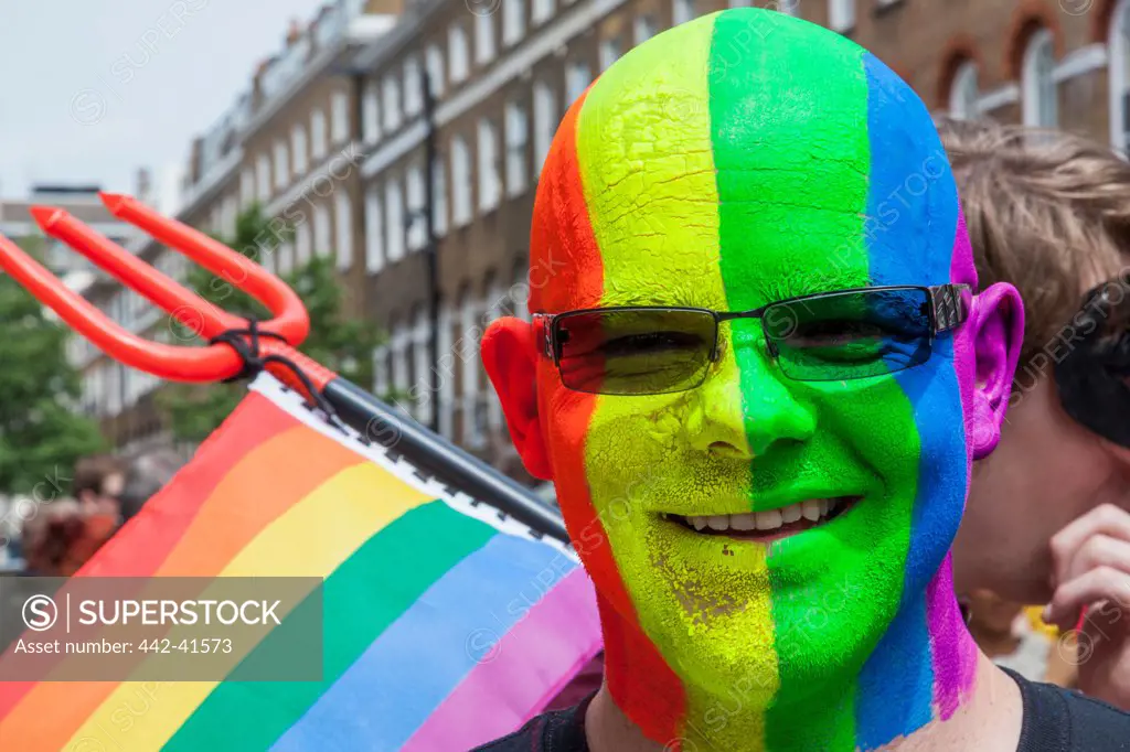 Man with face painted in the gay pride colors in the Annual Gay Pride Parade, London, England