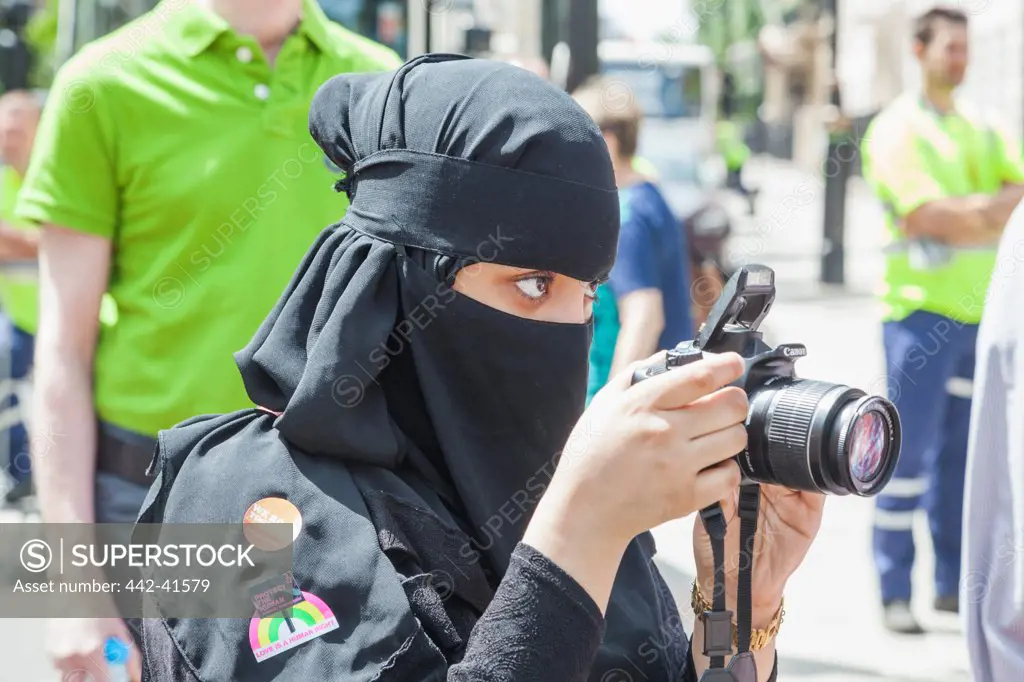 Muslim woman dressed in burka photographing in the Annual Gay Pride Parade, London, England