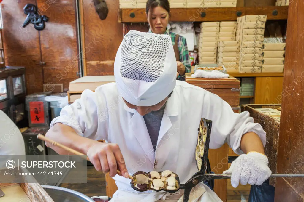 Japan, Honshu, Kanto, Tokyo, Asakusa, Sensoji Temple, Nakamise Street, Man Making Traditional Small Cakes