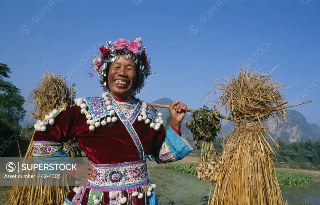 Portrait of a mid adult woman carrying straw on her shoulders, Guangxi Region, China