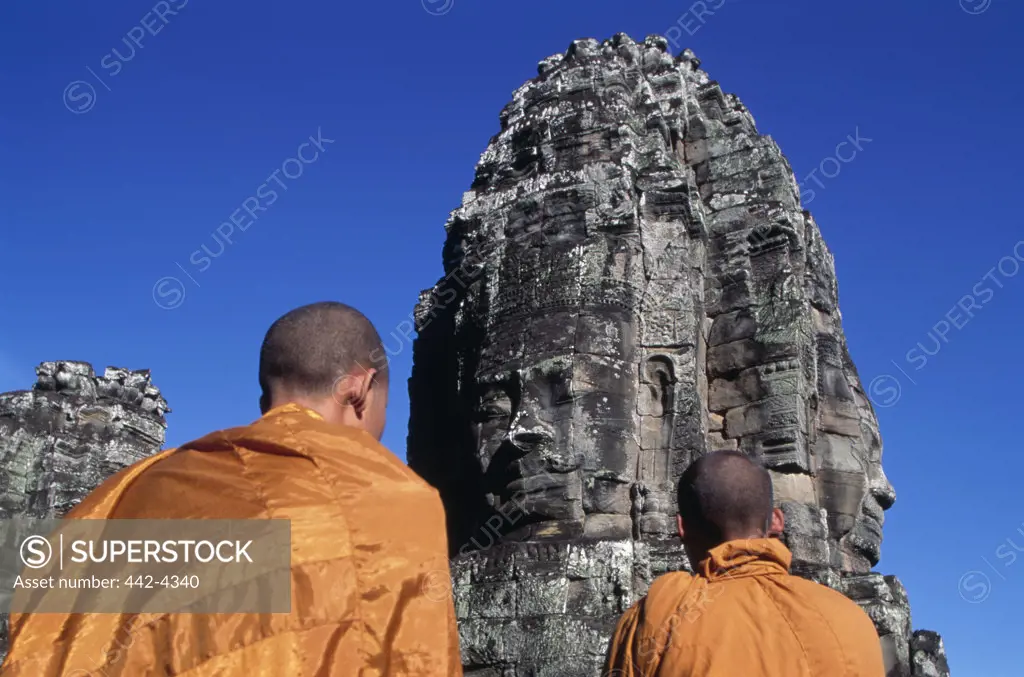Monks looking at the ruins of a temple, Bayon Temple, Angkor Wat, Cambodia