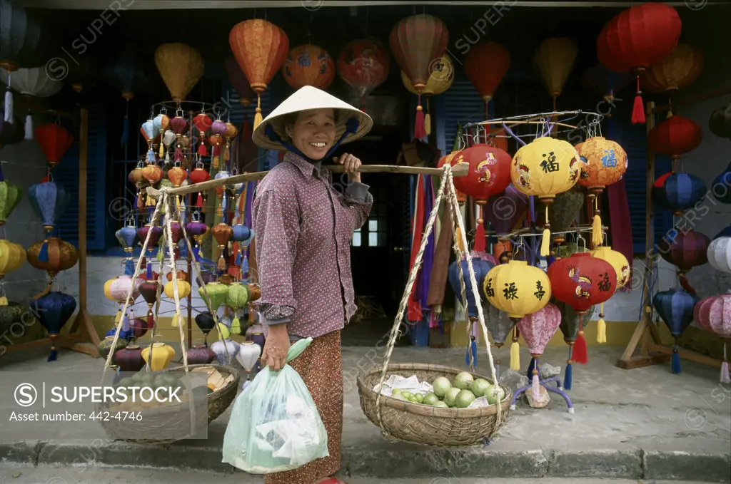 Mature woman carrying baskets on her shoulder, Hoi An, Vietnam