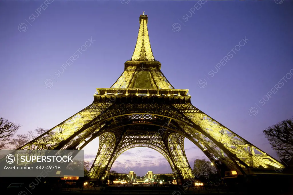 Low angle view of the Eiffel Tower lit up at dusk, Paris, France