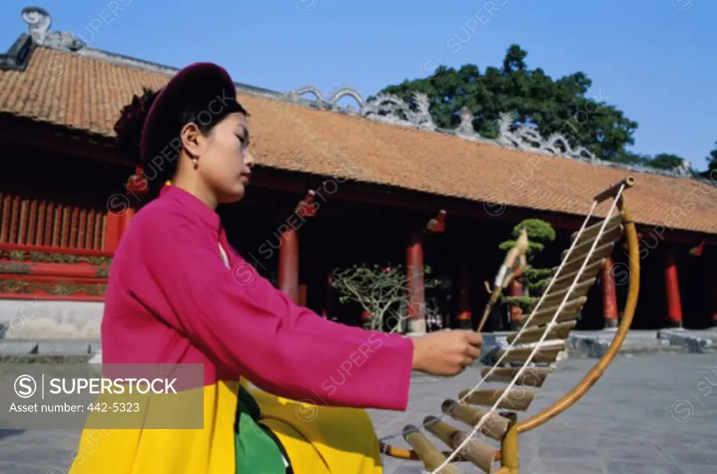 Young woman playing a bamboo instrument, Temple of Literature, Hanoi, Vietnam