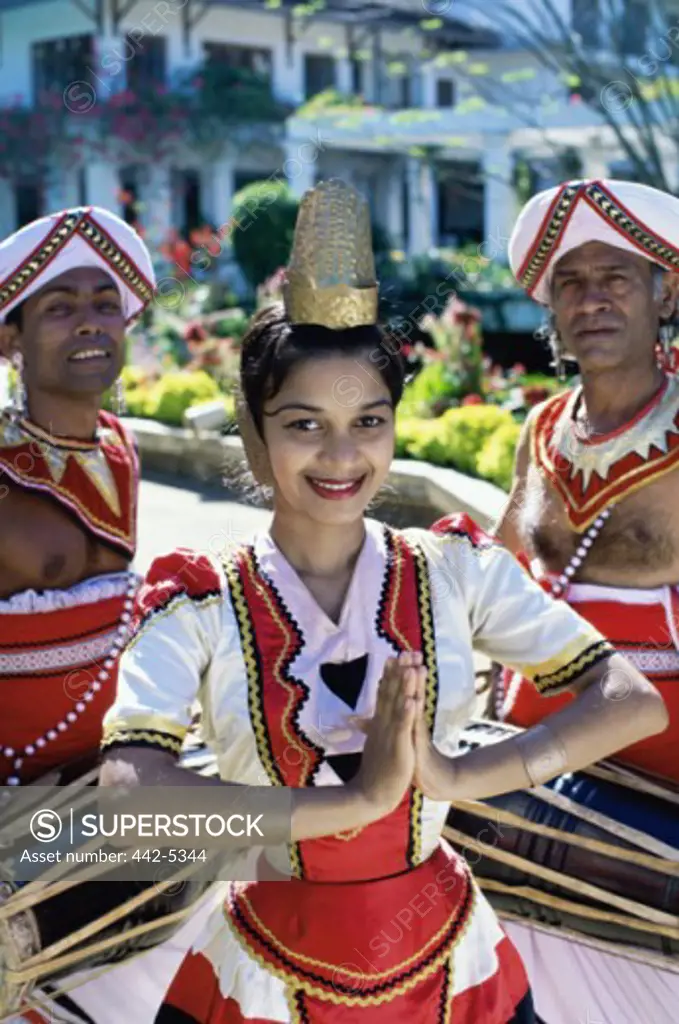 Portrait of a young woman with two men in traditional dance costumes, Kandy, Sri Lanka