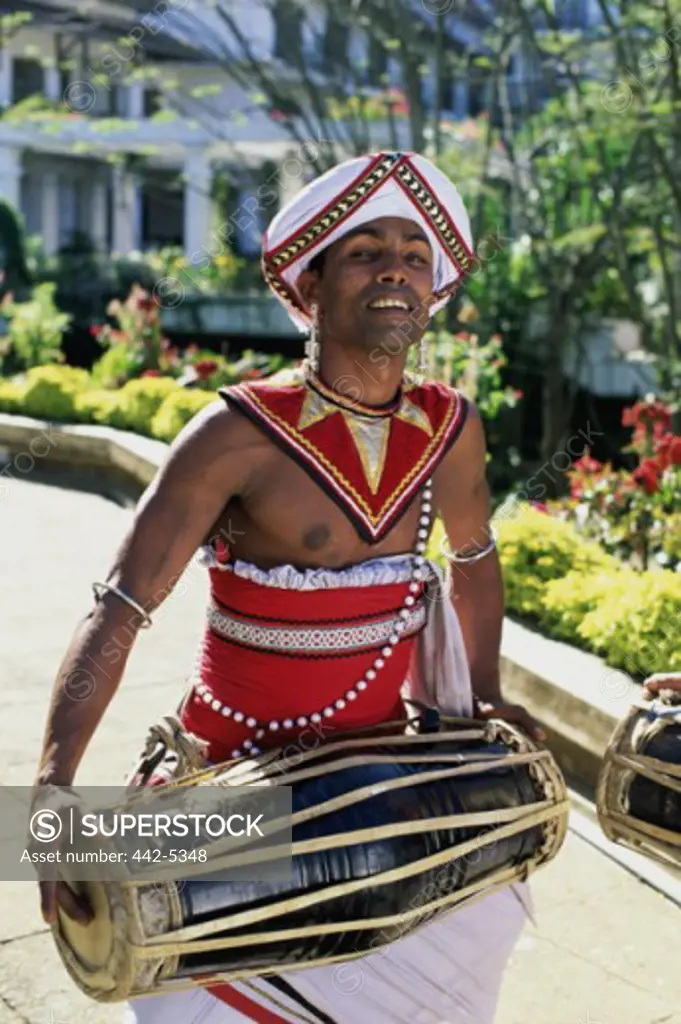 Portrait of a young man in a traditional costume playing a bongo, Kandy, Sri Lanka