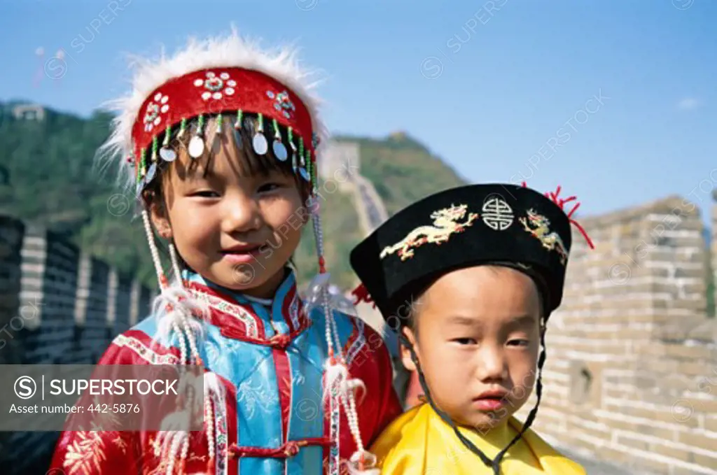 Close-up of a boy and girl dressed in Chinese costumes standing on the Great Wall, Mutianyu, Beijing, China