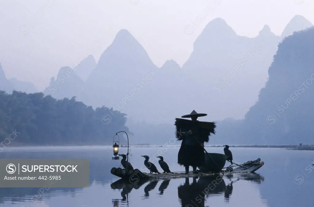 Cormorant fisherman standing on a raft on the Li River, Guilin, Yangshou, China