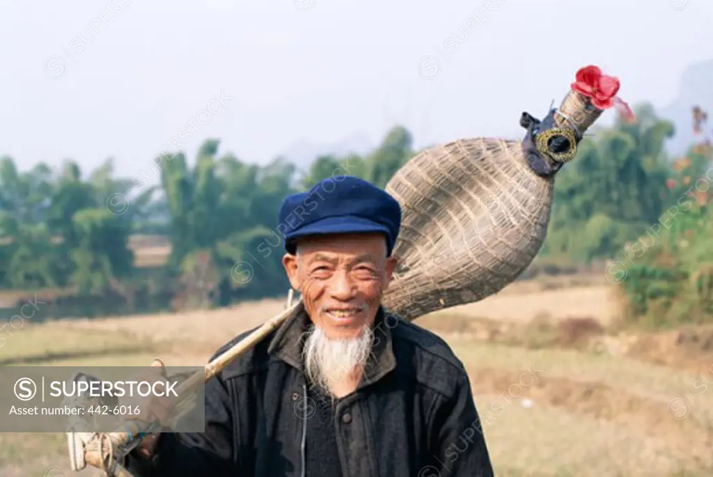 Senior man holding a traditional fishing basket, Guilin, Yangshou, China