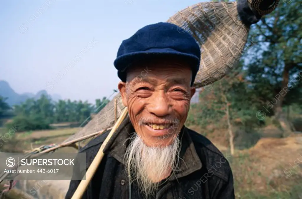 Close-up of a senior man holding a traditional fishing basket, Guilin, Yangshou, China