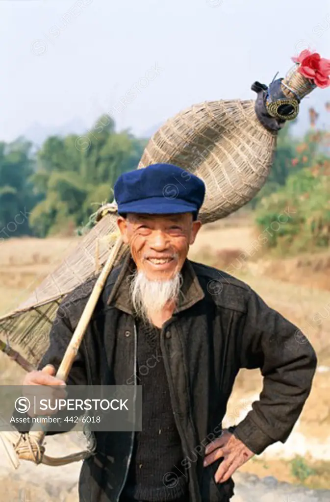 Senior man holding a traditional fishing basket, Guilin, Yangshou, China