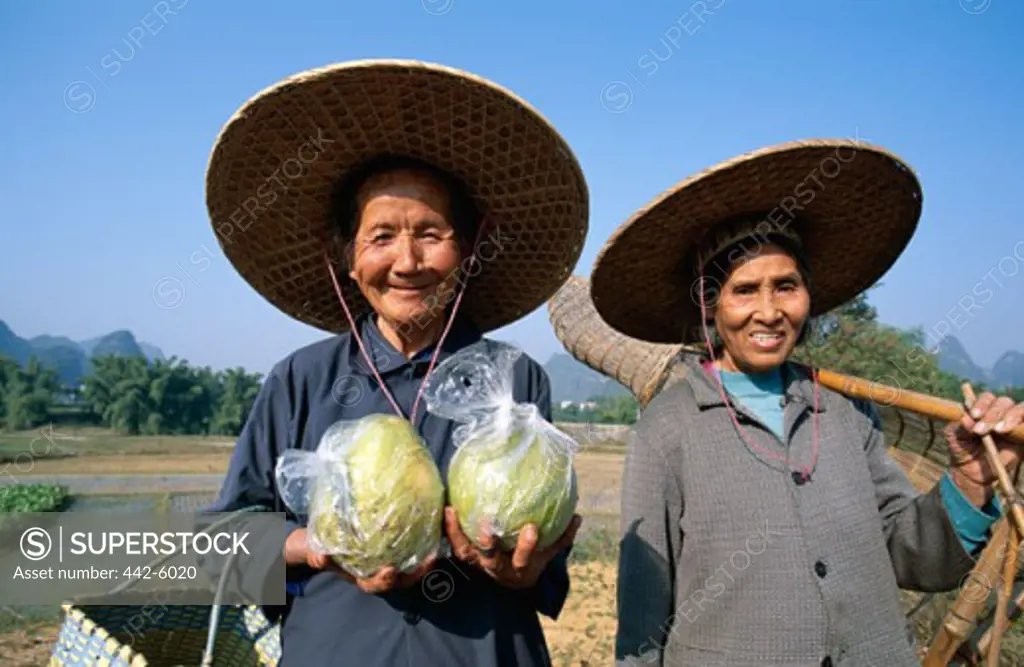 Two women holding pomelos and traditional fishing baskets, Guilin, Yangshou, China