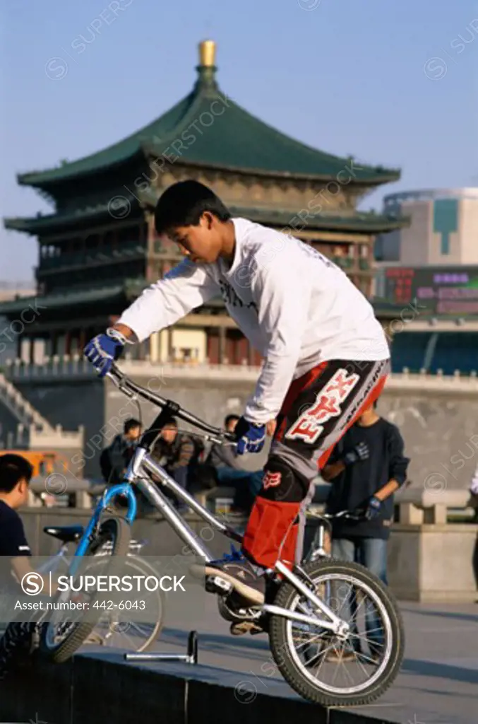 Teenage boy riding a BMX bike in front of the Bell Tower, Xi'an, China