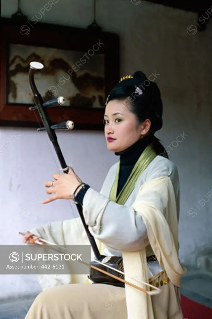 Young woman dressed in a traditional costume playing a musical instrument, Beijing, China