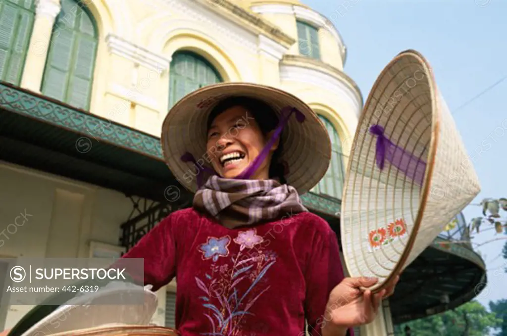 Mid adult woman selling traditional conical hats, Hanoi, Vietnam