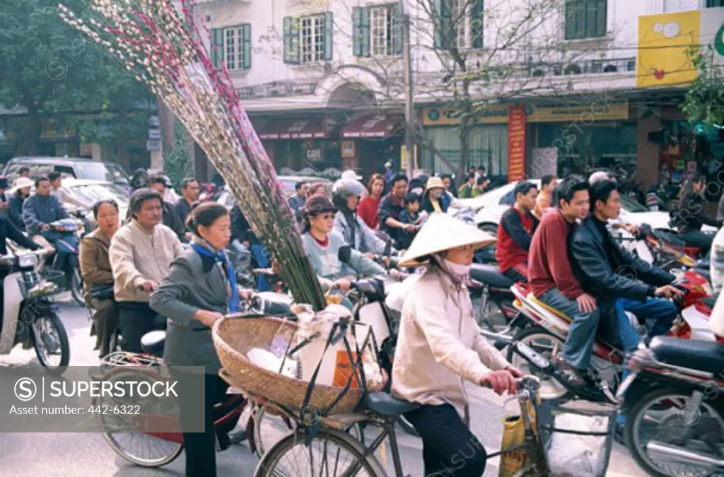 People on bicycles and motorcycles on a busy road in a market, Hanoi, Vietnam