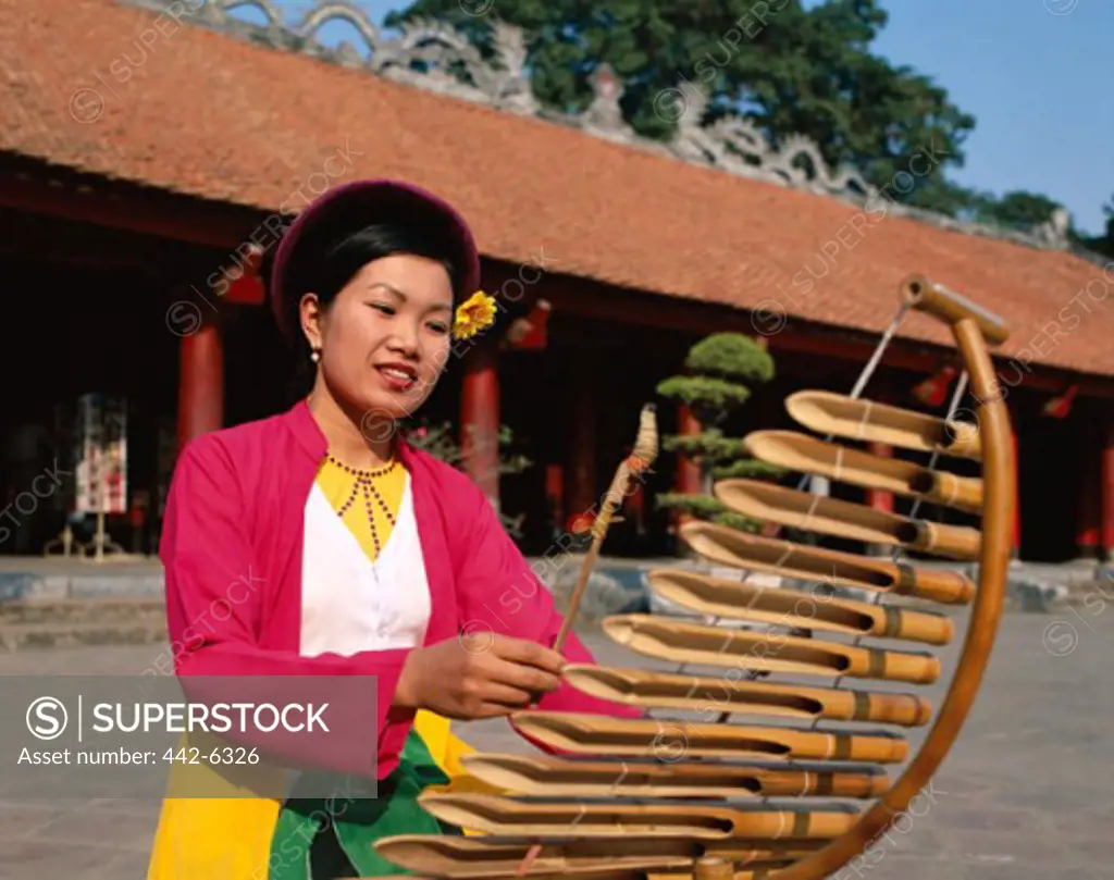 Young woman playing a bamboo musical instrument, Temple of Literature, Hanoi, Vietnam