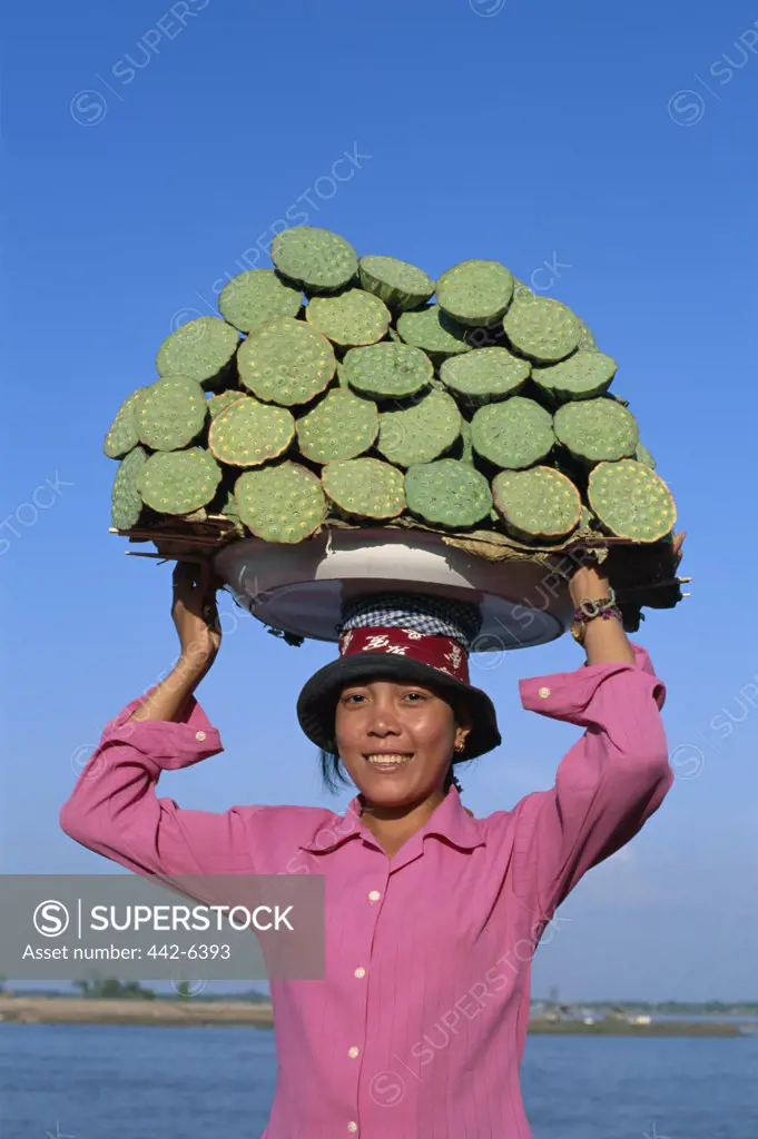 Portrait of a young woman carrying local produce on her head, Phnom Penh, Cambodia