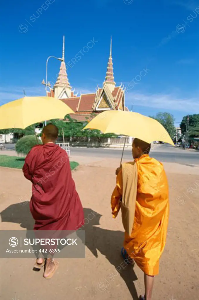 Rear view of two monks walking with umbrellas, Phnom Penh, Cambodia
