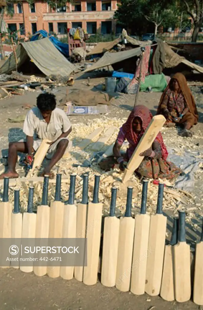 High angle view of a mid adult man and two mid adult women making cricket bats, Jaipur, Rajasthan, India