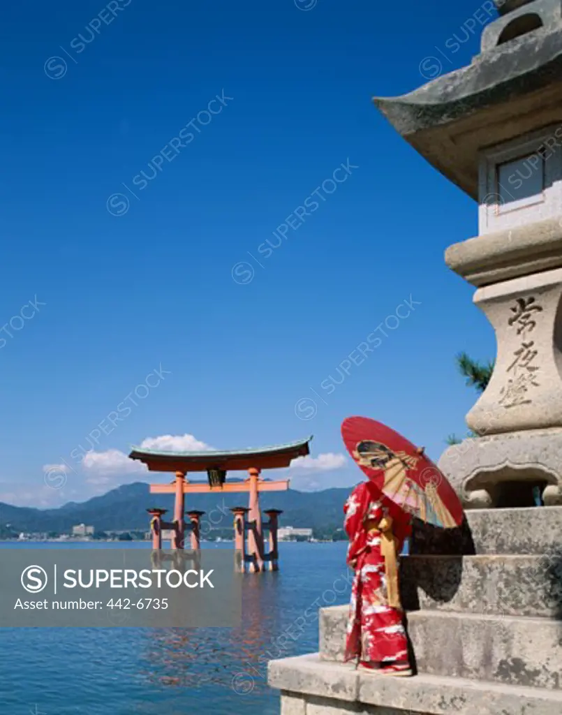Person standing near a shrine, Itsukushima Shrine, Miyajima Island, Honshu, Japan
