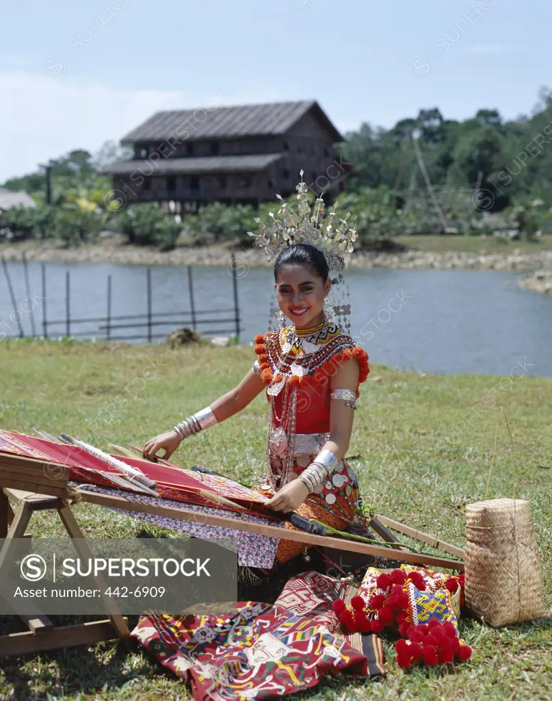 Iban woman dressed in a traditional costume weaving, Sarawak Cultural Village, Sarawak, Malaysia