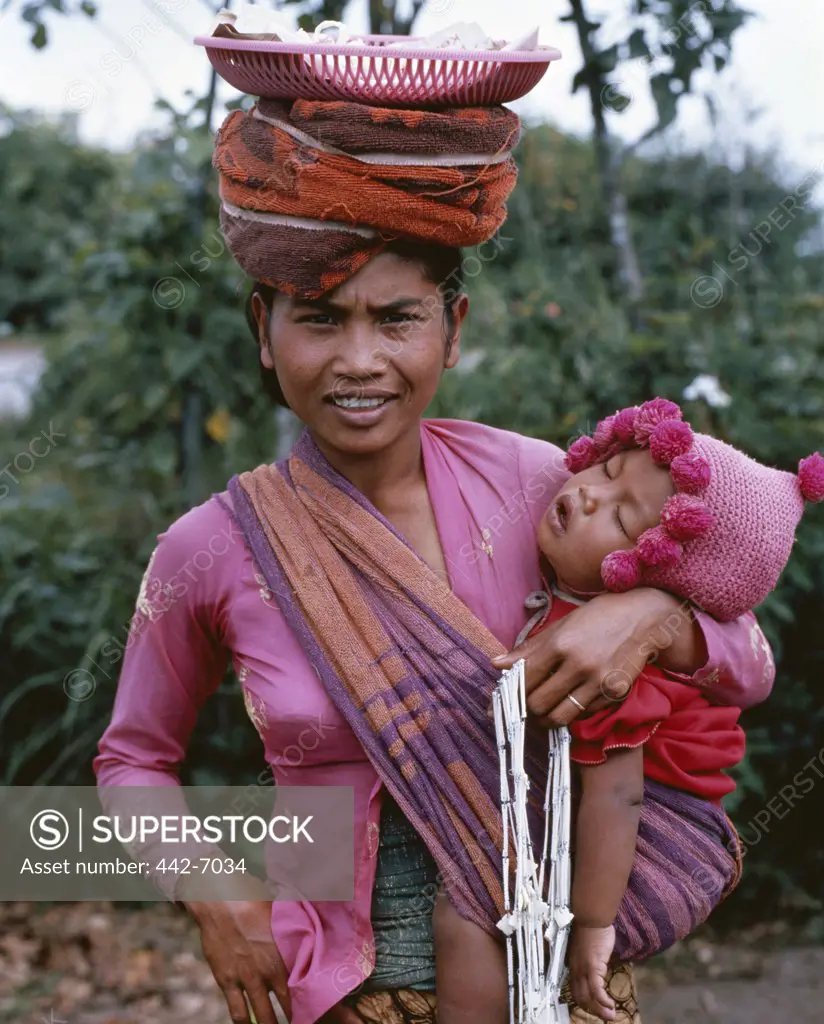 Portrait of a mid adult woman holding her baby, Kintamani Market, Bali, Indonesia