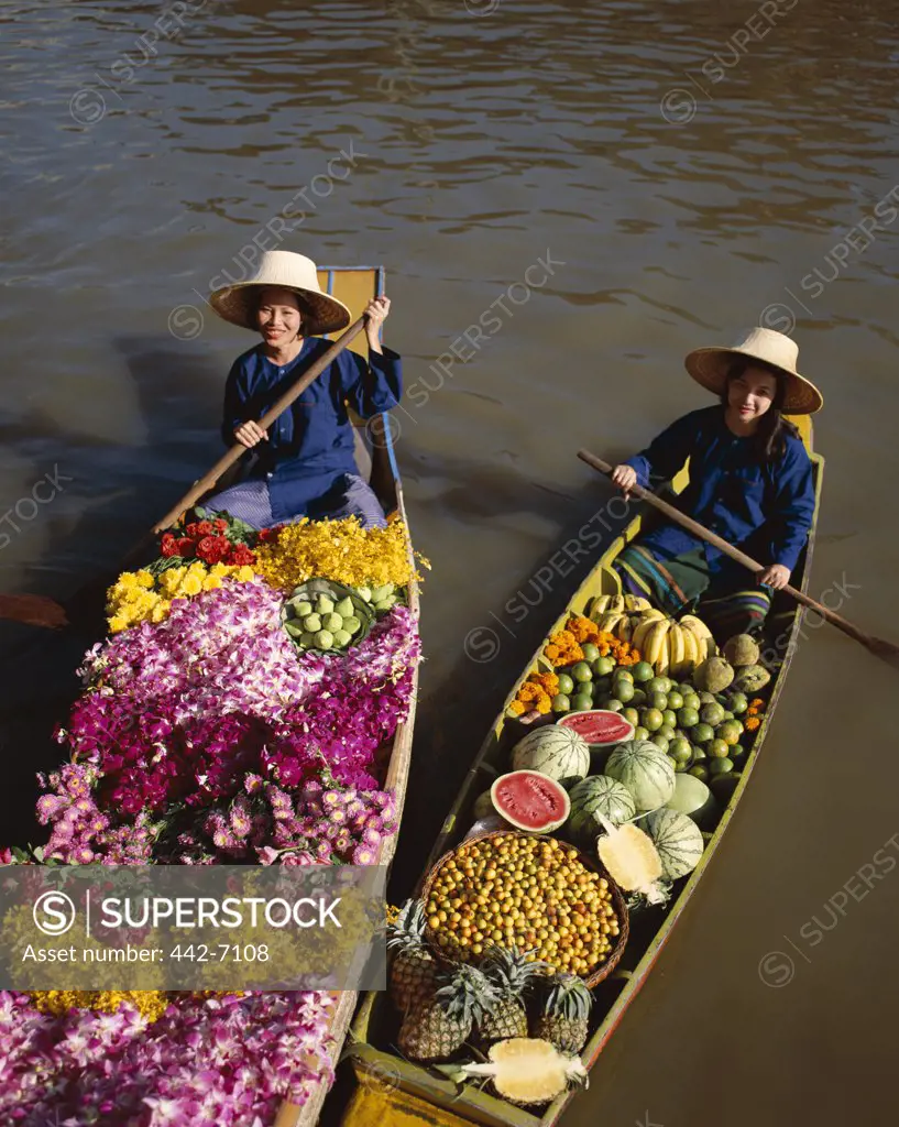 Two female vendors in boats selling fruit and flowers, Floating Market, Damnoen Saduak, Bangkok, Thailand