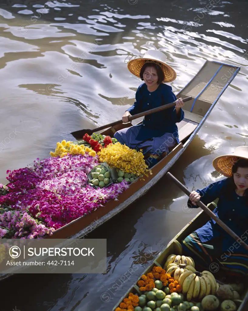 Two female vendors in boats selling fruit and flowers, Floating Market, Damnoen Saduak, Bangkok, Thailand