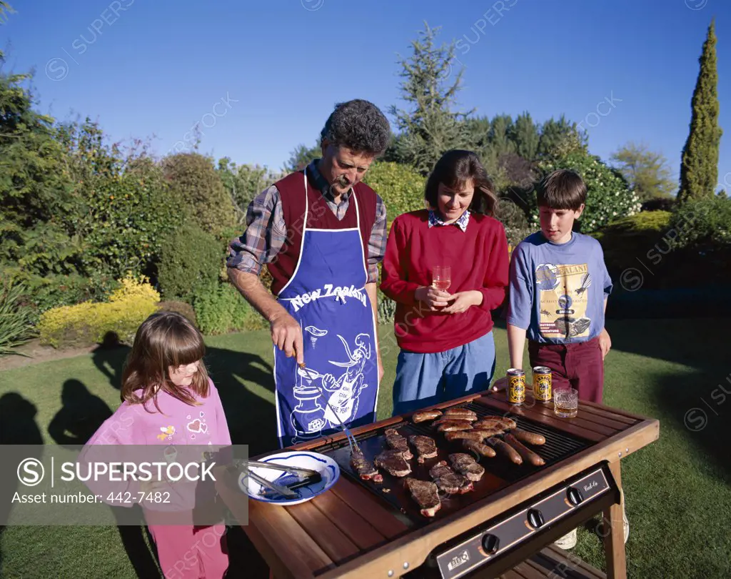 Family in front of a barbeque grill, North Island, New Zealand