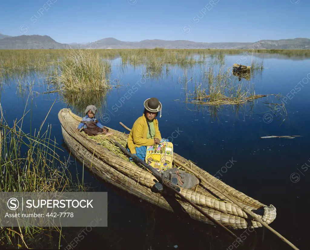 Mid adult woman sitting with her son in a traditional reed boat, Lake Titicaca, Peru