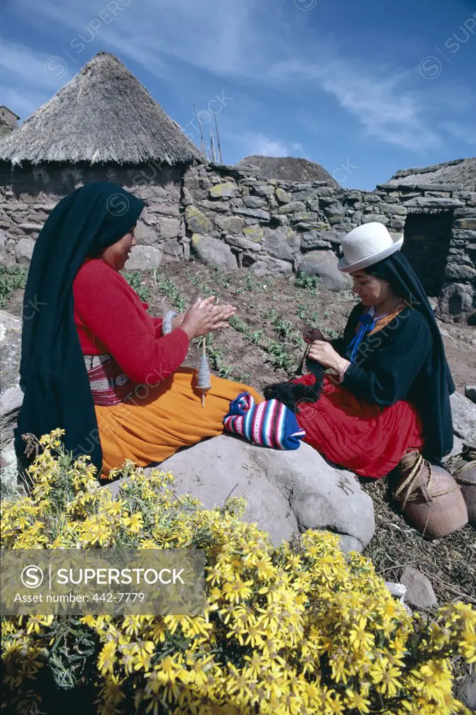Two mid adult women spinning wool, Lake Titicaca, Taquile Island, Peru